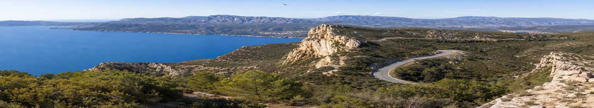 Panorama sur la baie de Cassis et un virage de la route des Crêtes, un rapace en vol